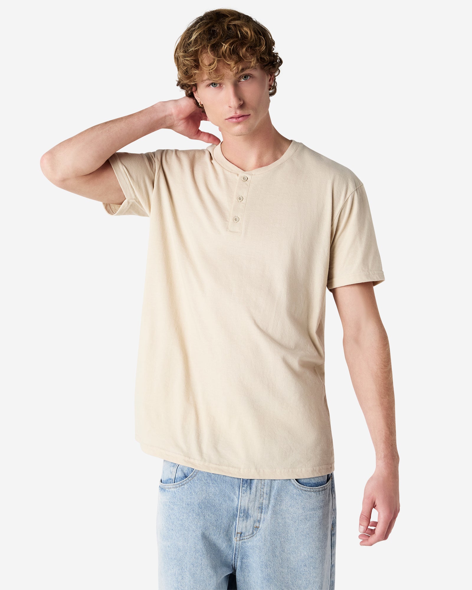 Front view of man wearing unisex bone coloured American Apparel Henley T-shirt looking straight ahead with right hand behind head
