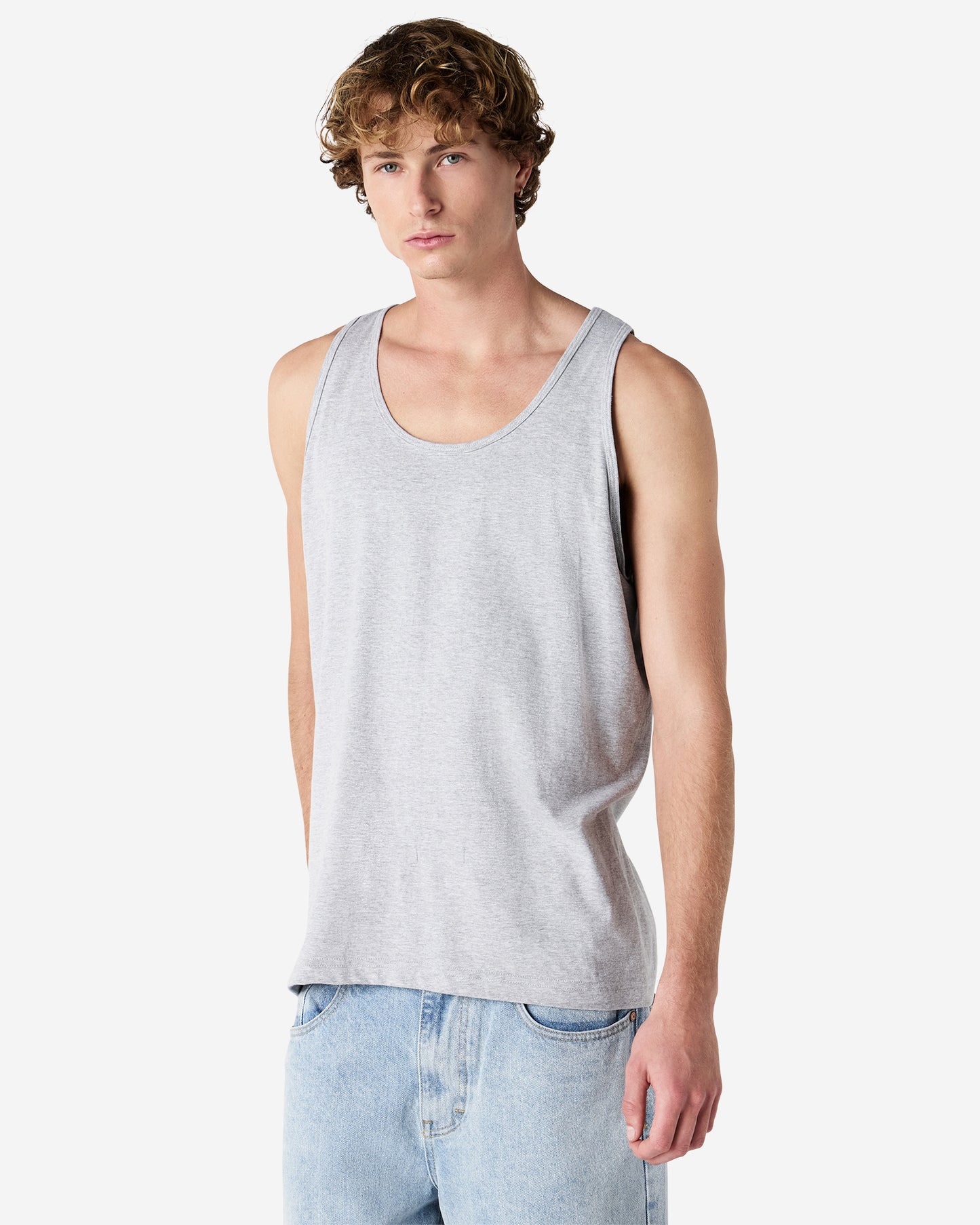 Front view of man wearing grey American Apparel Unisex Tank Top looking forward with right hand behind back