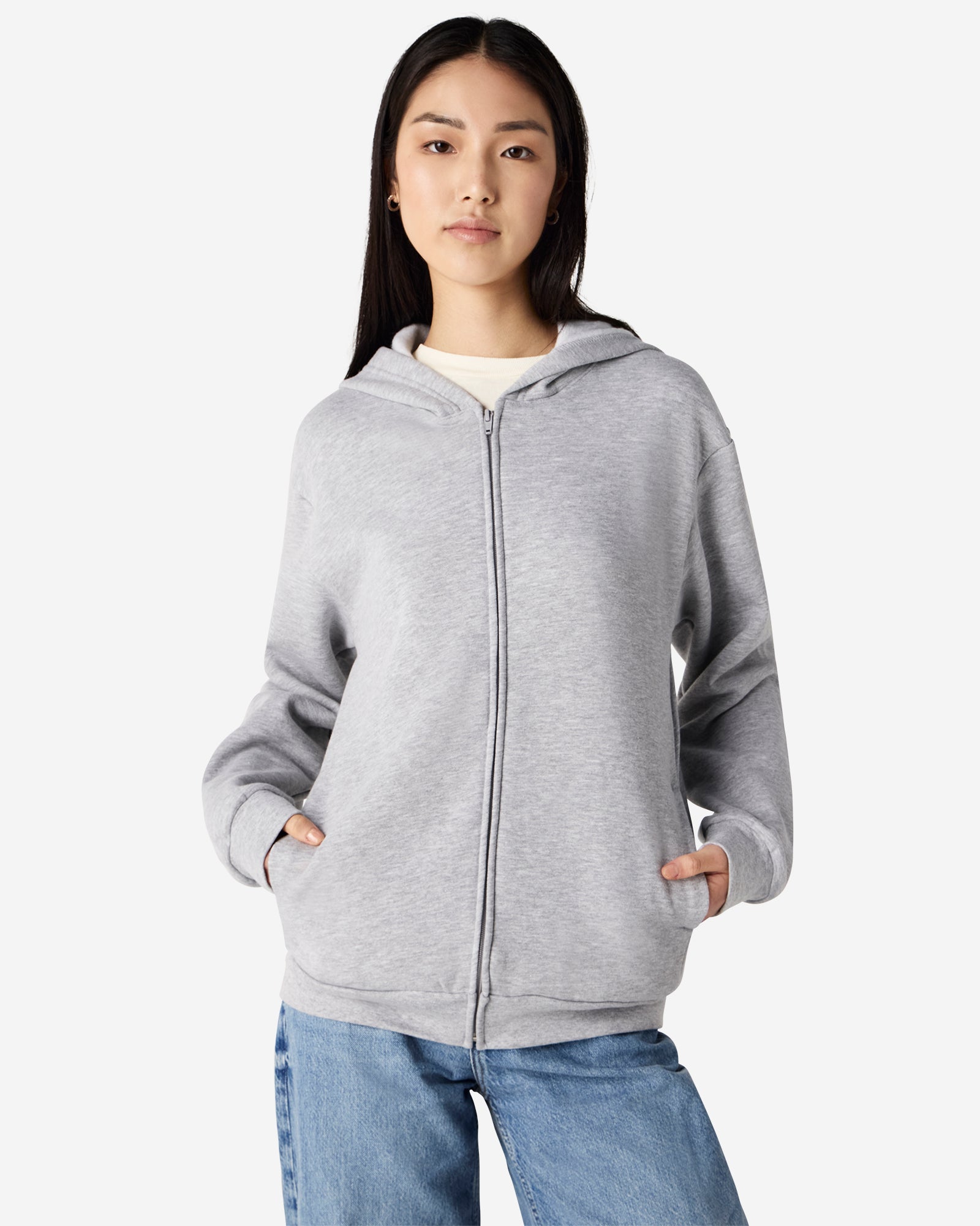 Front view of woman wearing grey American Apparel Zip-Up Hoodie fully zipped with hands casually in pockets