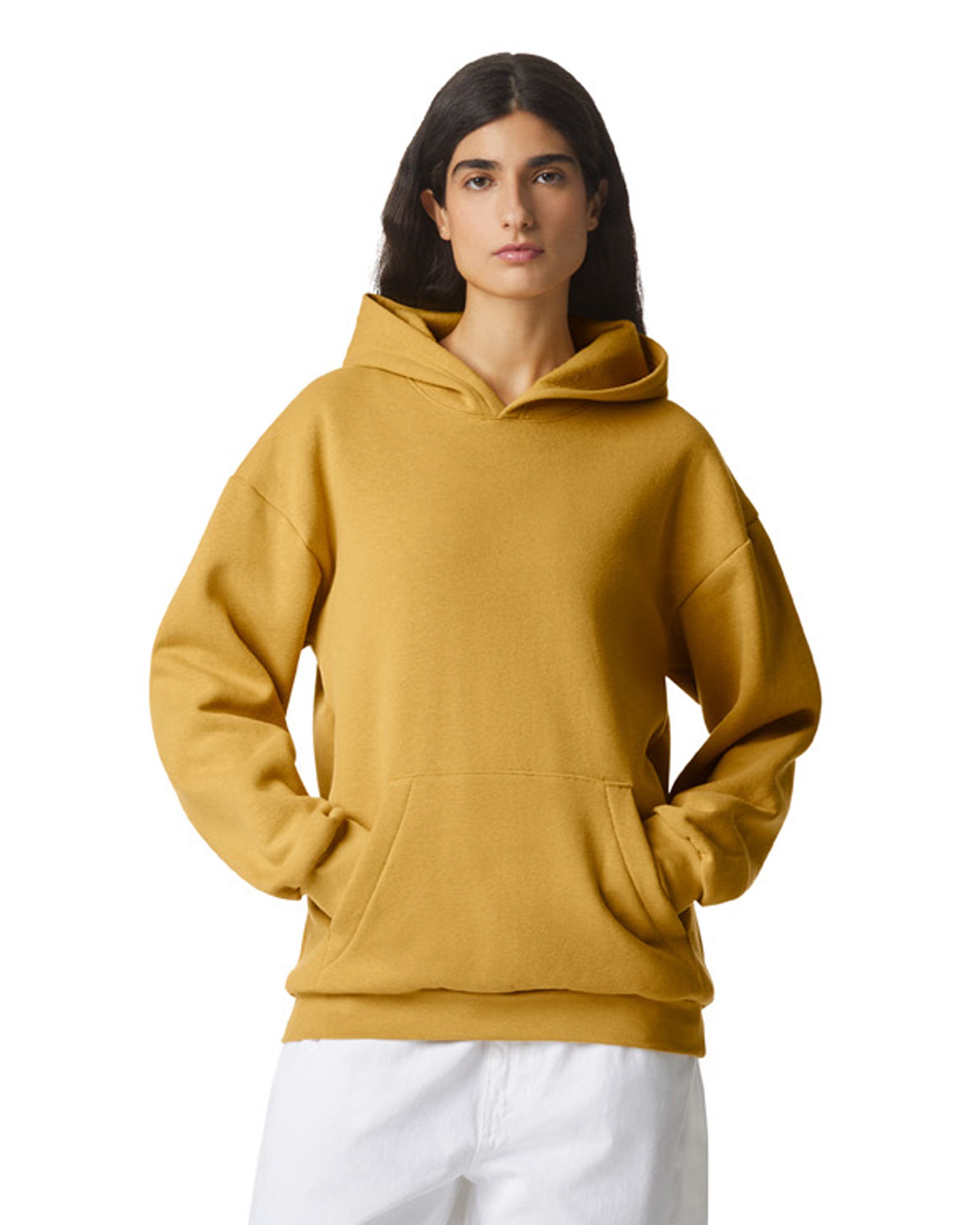 Front view of woman wearing mustard American Apparel RF498 Unisex Pullover Hoodie looking frontward with hands in pockets