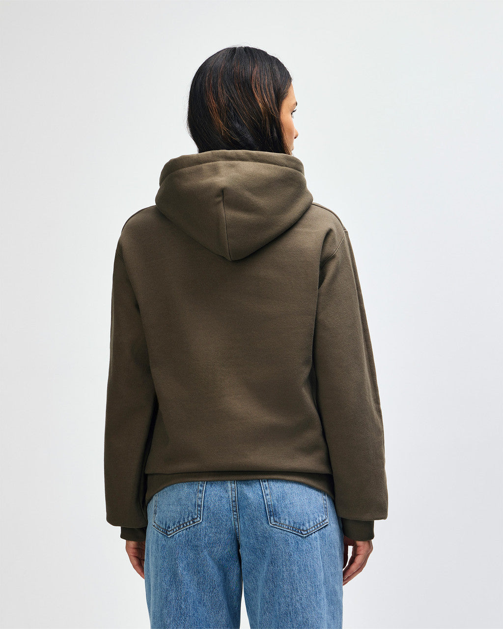 Back view of woman wearing olive Gildan Hammer Maxweight Adult Hooded Sweatshirt looking towards the right