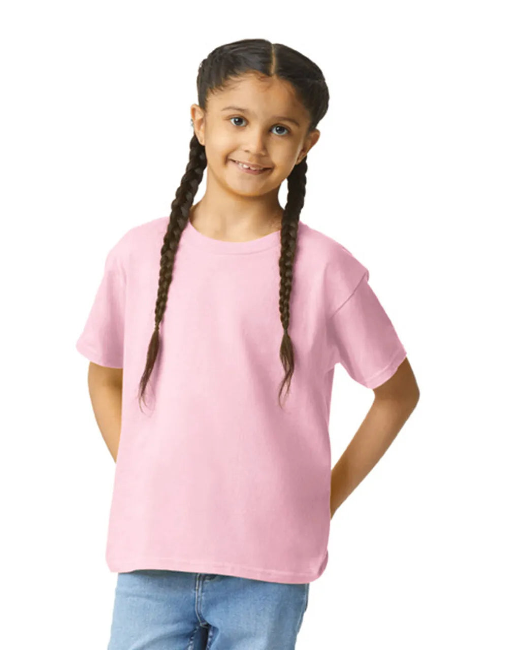 Front view of youth wearing a pink Gildan 64000B Youth Softstyle® T-Shirt smiling with hands in back pockets