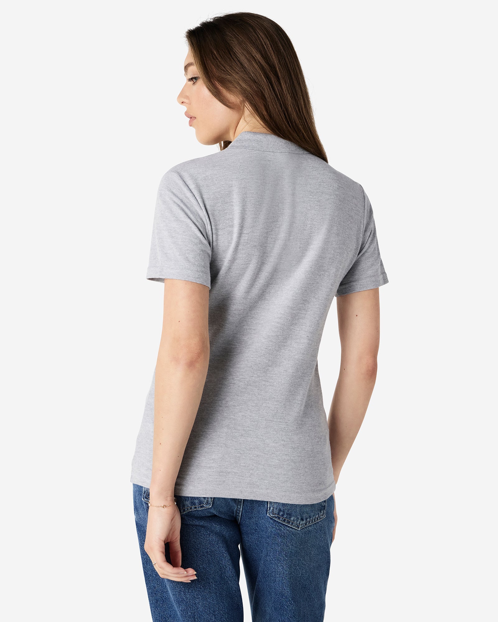 Back view of woman wearing grey Gildan Ladies Pique Polo Shirt looking over left shoulder