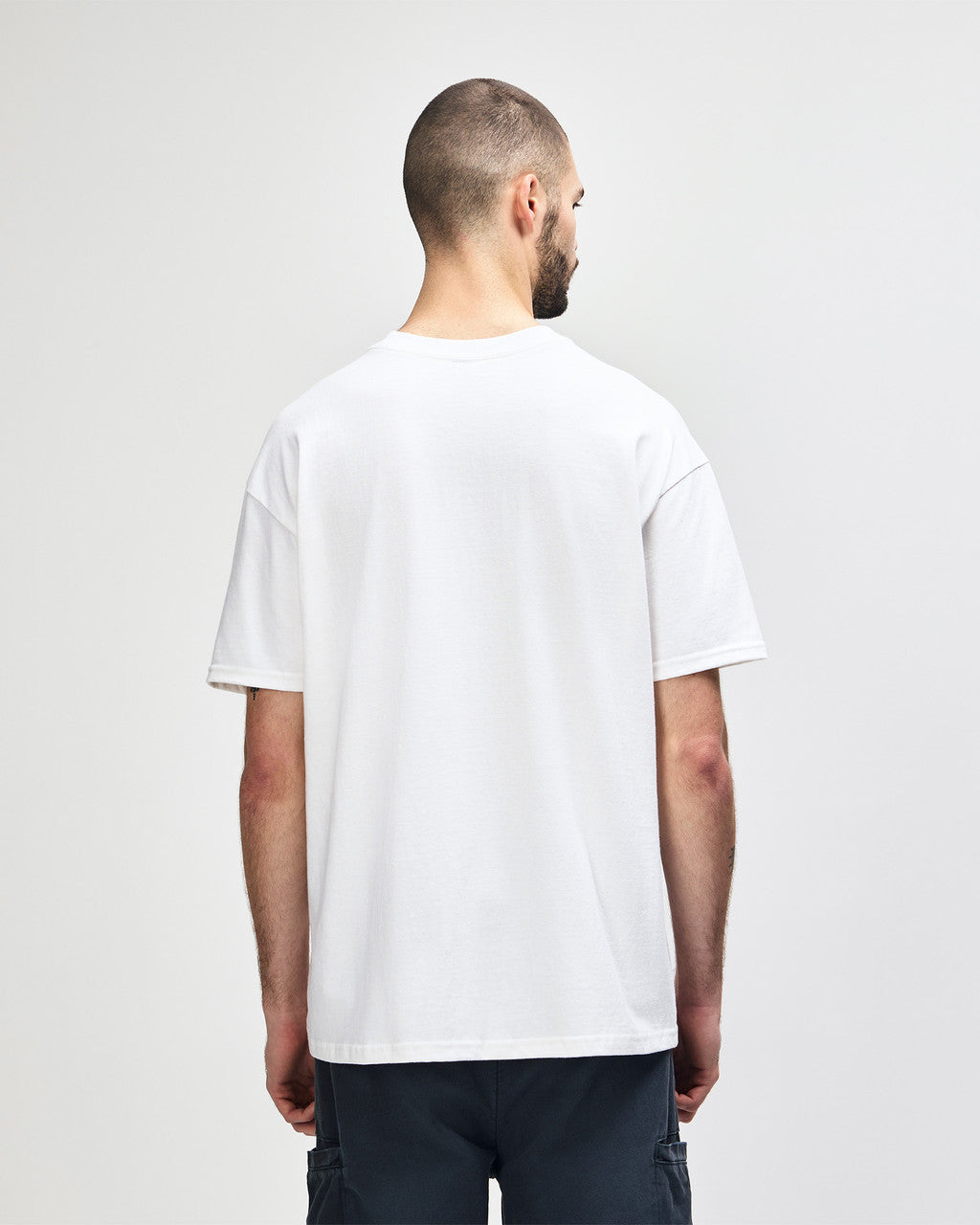 Back view of bearded man wearing white Gildan Hammer 7500 Adult Oversize Maxweight T-Shirt looking right